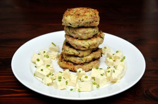 Lautasella pihvipino, jota ympäröi sipulinversoin koristeltuja salaattijuustokuutioita.