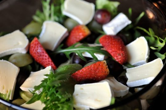 Kulhossa jääsalaattia, rucolaa, valkohomejuustoa, viinirypäleitä ja mansikka.