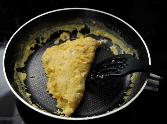 Munakas paistinpannulla muovisen puuhaarukan vieressä.