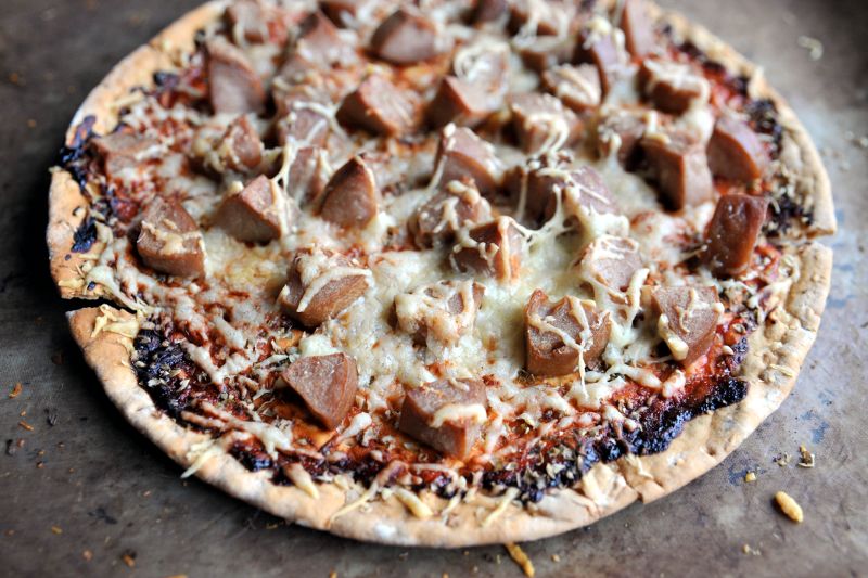 Pyöreä pitsa, jonka päällä makkaraa, tomaattikastiketta ja juustoa.