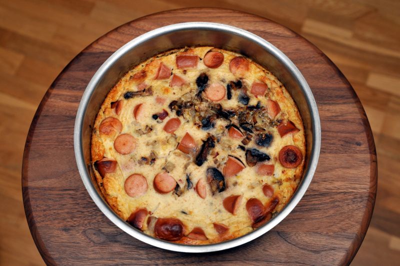 Nakeilla ja sienillä täytetty pannukakku pyöreässä vuoassa.