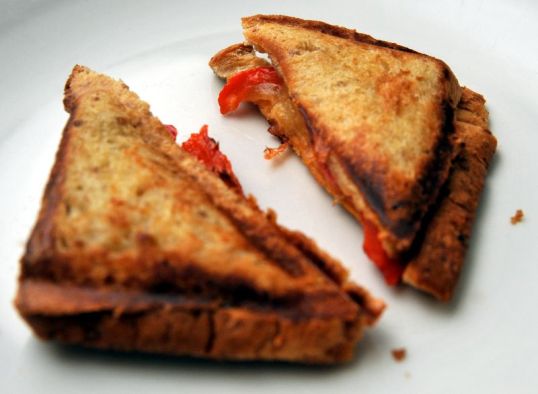 Päällekkäiset ja puolitetut paahtoleivät, joiden sisällä juustoa ja paprikaa.