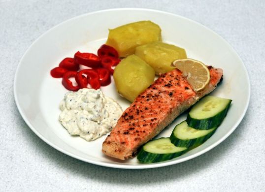 Lautasella paistettua lohta, keittettyjä perunoita, ranskankermadippiä, paprikaa ja kurkkua.