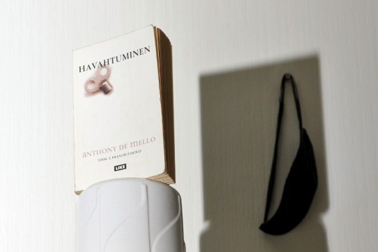 Jalustalle nostettu Havahtuminen-kirja heittää varjonsa mustien silmälappujen päälle.