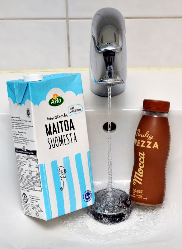 Posliinialtaassa maitotölkki, valuvaa vettä ja kahvijuomapullo.