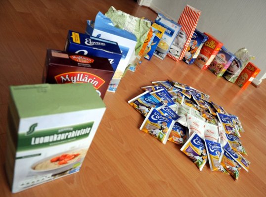 Lattialla puurohiutalepakkauksia jonossa ja pikapuuropusseja läjässä.