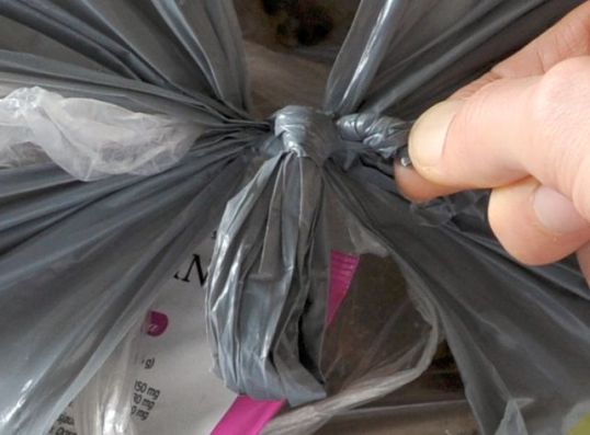 Roskapussin solmua avataan kiertämällä sormilla pussin sankaa.