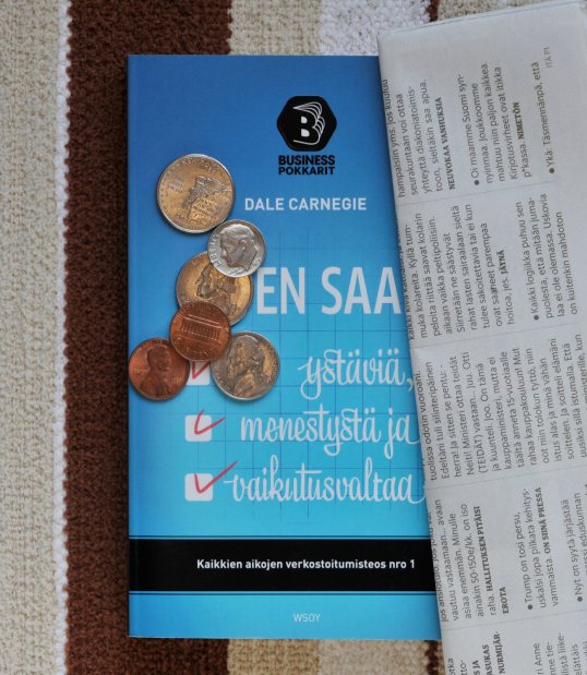 Miten saan ystäviä, menestystä ja vaikutusvaltaa -kirjan päällä yhdysvaltalaisia kolikoita ja HS Metro -lehden tekstiviestipalstaa.