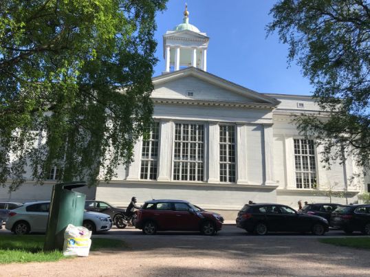 Valkoinen muovikassi roskakorin vieressä. Taustalla Helsingin vanha kirkko.