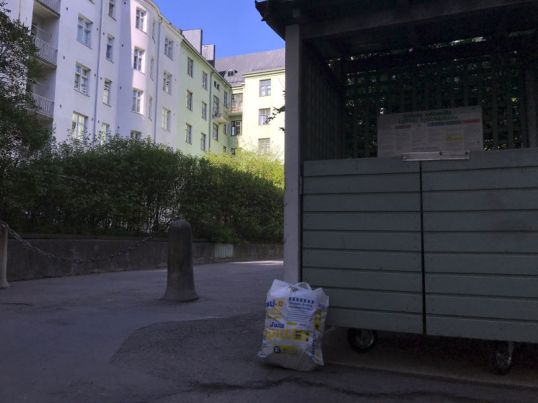 Valkoinen muovikassi nojaa jätekatokseen Sonckin korttelissa.