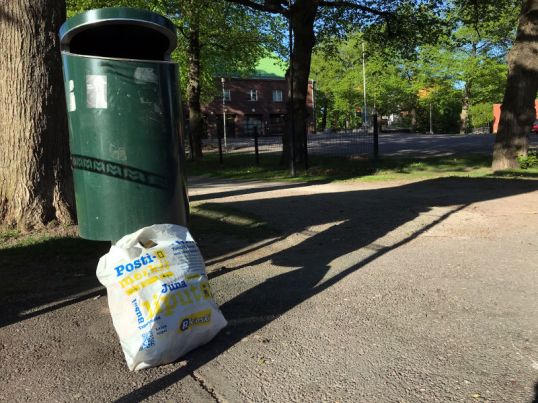 Valkoinen muovikassi roskakorin vieressä Käpylän pelastusaseman edessä.