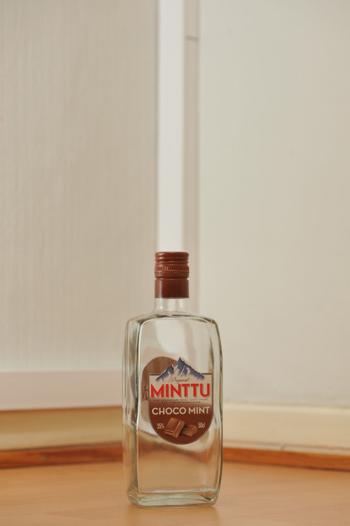 Tyhjä Minttu Choco Mint -viinan 0,5 litran kirkas lasipullo puunvärisellä lattialla.