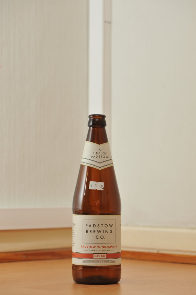 Tyhjä Padstow-oluen 0,568 litran ruskea lasipullo puunvärisellä lattialla.