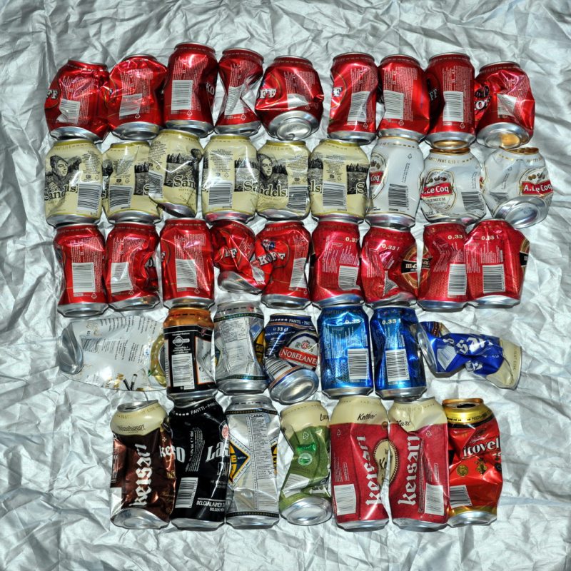 41 puristunutta juomatölkkiä hopeanvärisen peitteen päällä.