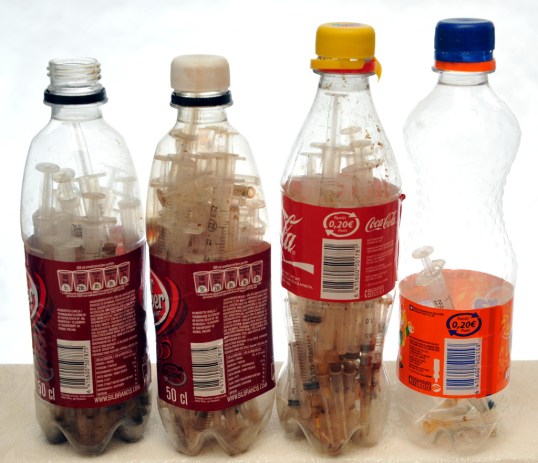 Neljä muovipulloa, joiden sisällä on paljon injektioruiskuja.