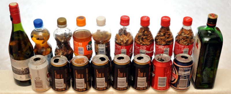 Lasipulloja, muovipulloja ja juomatölkkejä, joiden sisällä on savukkeenpätkiä ja osassa myös nestettä.