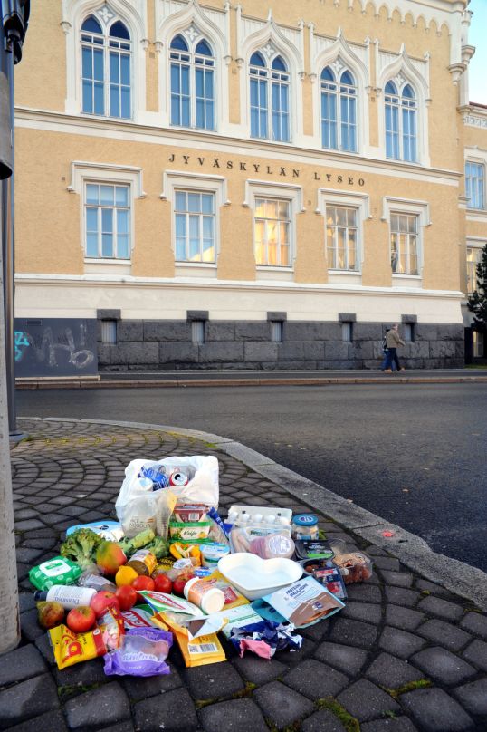 Etualalla dyykkilöytöjä katukiveyksen päällä, taustalla Jyväskylän lyseon vanha julkisivu.