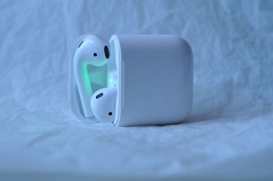 Applen langattomat Airpods-kuulokkeet avatussa latauskotelossa valkoista lakanaa vasten.