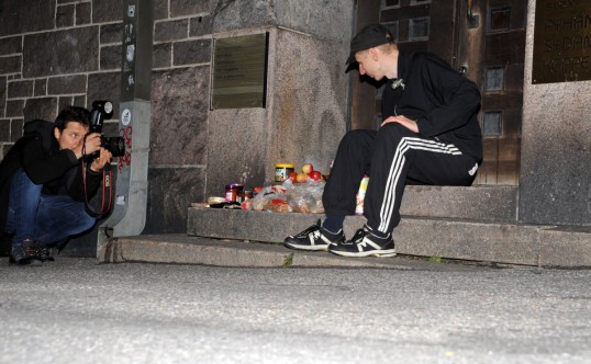 Sami Kero valokuvaa HEO-kansanopiston portailla dyykkisaaliinsa vieressä istuvaa Onni Tonkijaa.