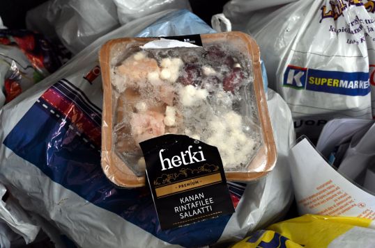 Jäätynyt kananfileesalaattipakkaus roskapussien päällä.