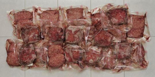 Parikymmentä pakastettua jauhelihapakettia valkoisten laattojen päällä.