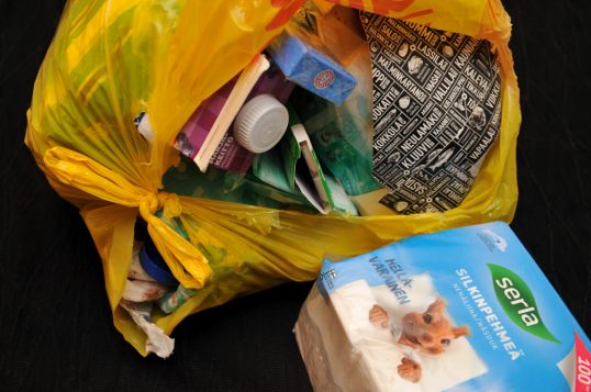 Auki repäistyssä muovikassissa muun muassa avaamattomat pakkaukset marjakeittoa, purukumia ja pastilleja. Kassin ulkopuolella paketti nenäliinoja.