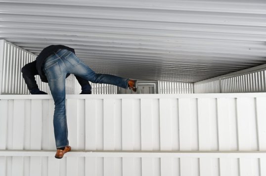 Onni Tonkija kiipeää valkeaan jätekatokseen.