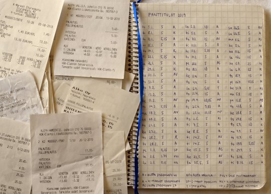 Muistikirjaan merkitty vuoden 2019 panttituloja. Vieressä pullonpalautuskuitteja.