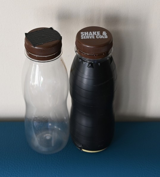 Kaksi pientä muovipulloa. Toisessa ei ole etikettiä, ja korkin päällä on musta teippi. Toinen on ympäröity täysin mustalla teipillä, mutta korkin teksti on näkyvissä.