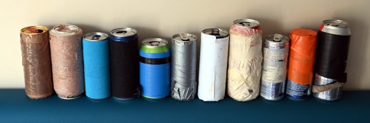 Yksitoista tölkkiä, joiden tekstejä on peitetty eri tavoin teippaamalla.