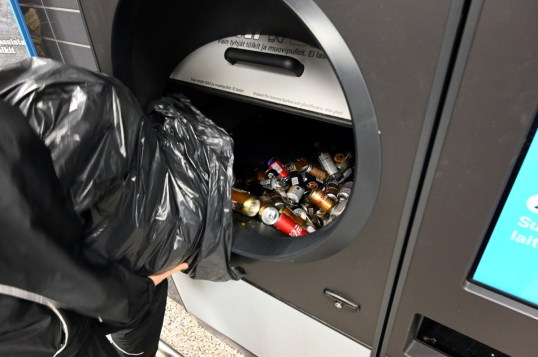 Tölkkejä ja pulloja kaadetaan jätesäkistä Tomra R1 -palautusautomaattiin.