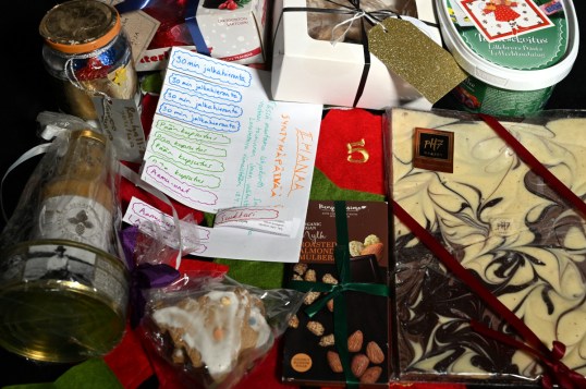 Suklaata, leivonnaisia ja muita elintarvikkeita lahjakääreissä. Lisäksi käsin paperille tehtyjä lahjakortteja.