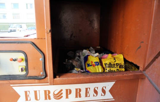 Jätepuristin, jonka avatusta luukusta näkyy roskapusseja.