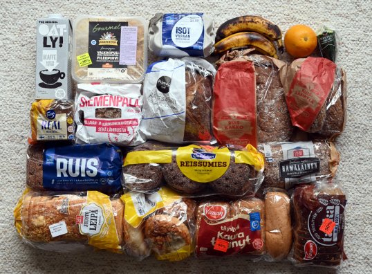 Toistakymmentä pussia leipää, tölkki kaurajuomaa, paketti broilerin fileepihvejä, rasia kananmunia, kaksi banaania, appelsiini ja pätkä kurkkua.